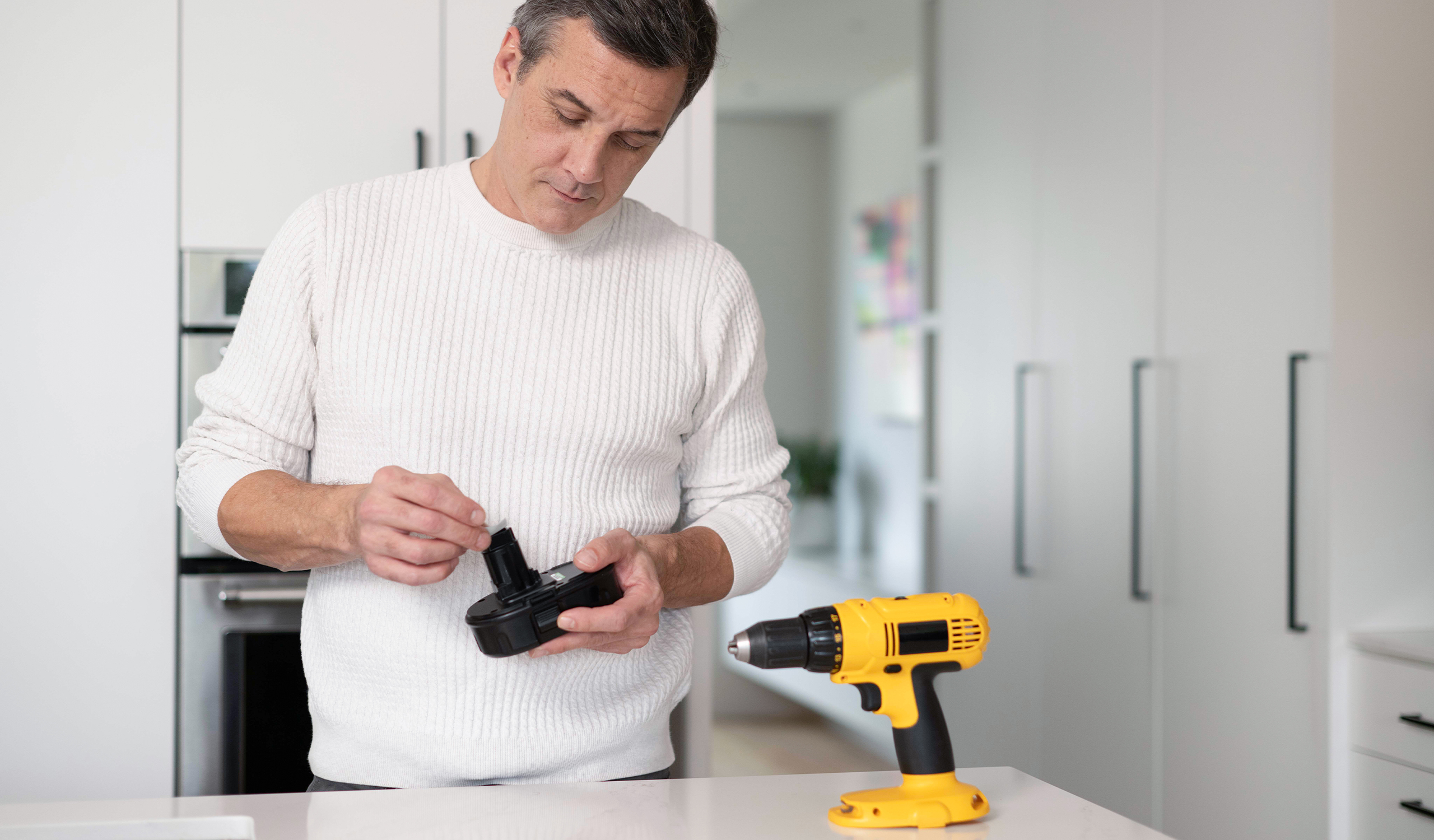 Man protecting yellow drill battery