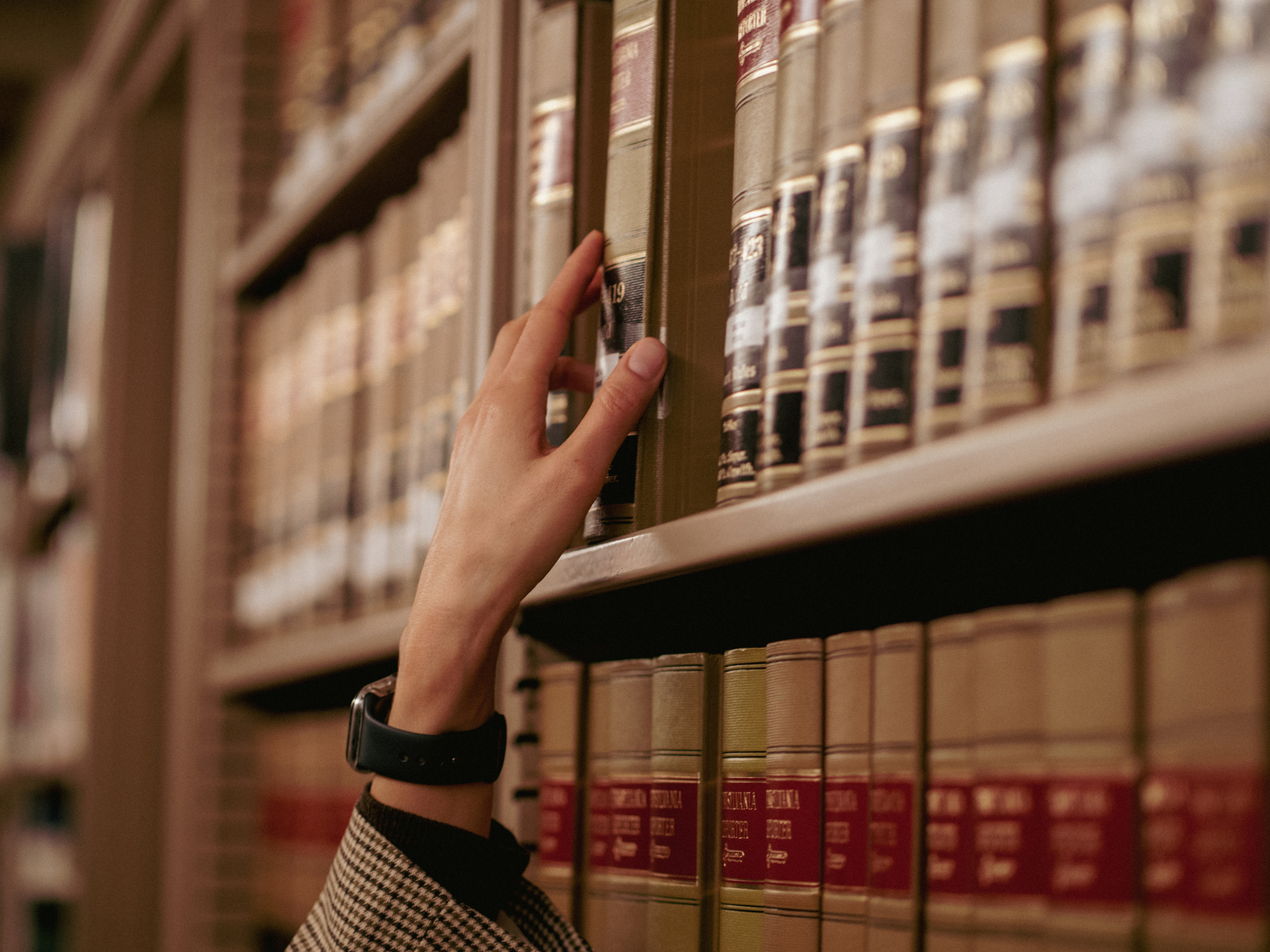 Person reaching for a book in a library